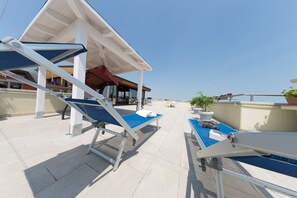 A rooftop terrace with two sun loungers, a table, and a potted plant. - Hotel Tessarin (Taglio di Po)