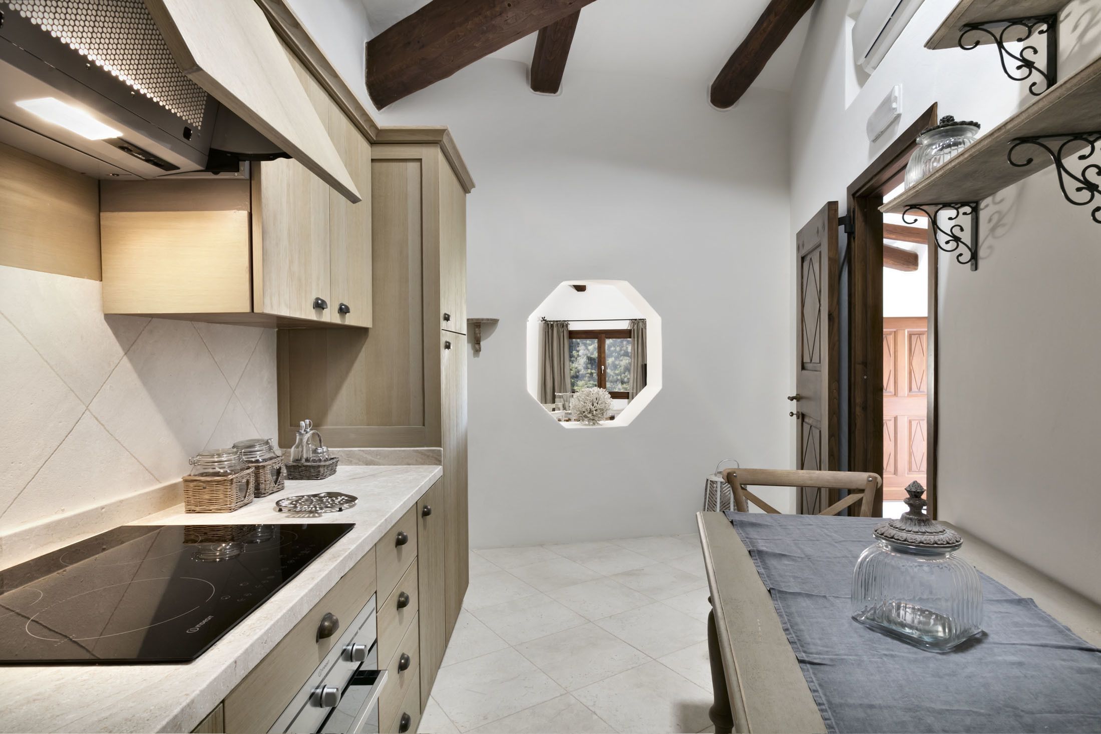 A kitchen with a built-in stove, wooden cabinets, and a small window.