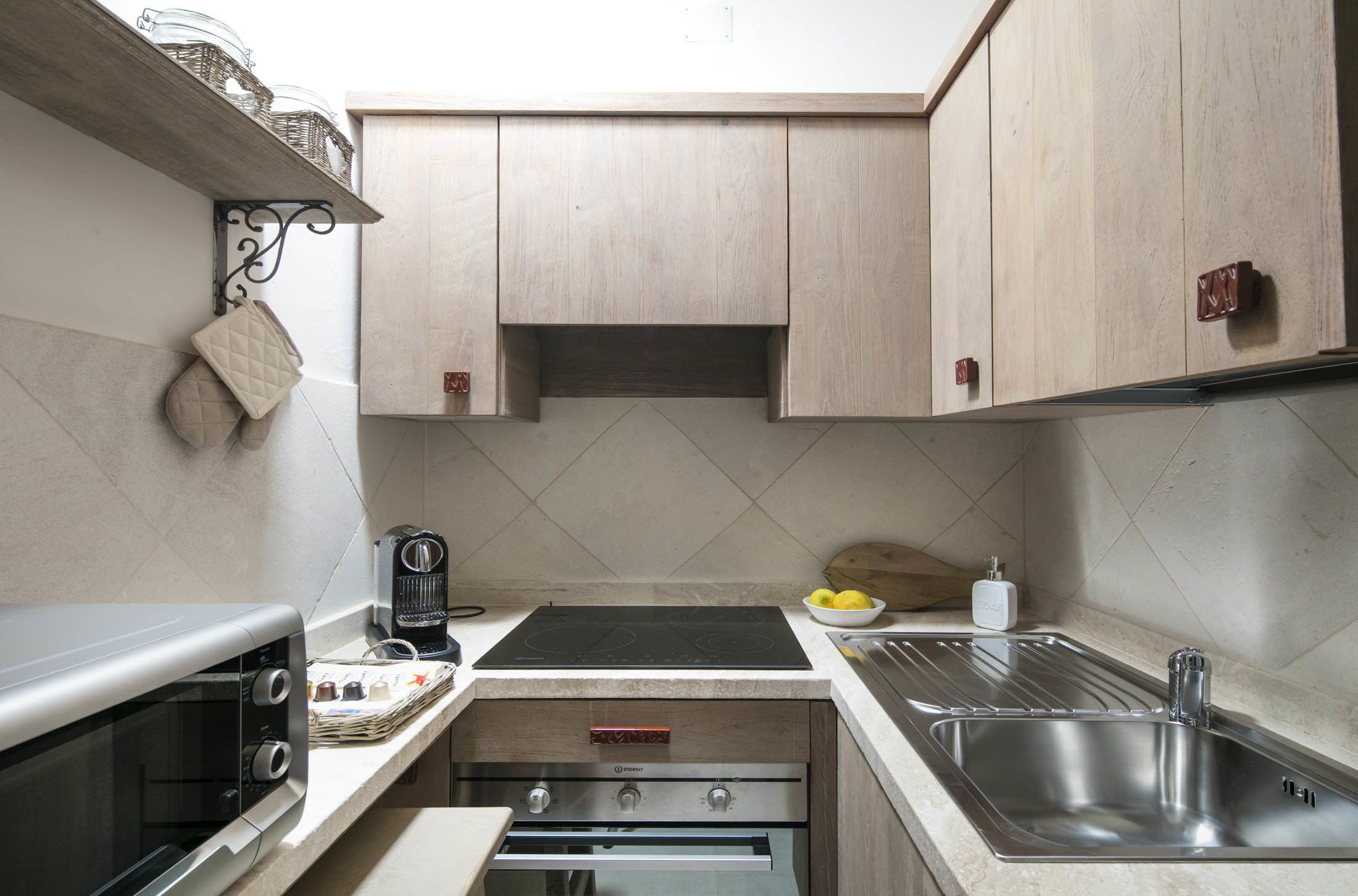 A compact kitchen with a built-in oven, a stovetop, and a sink.