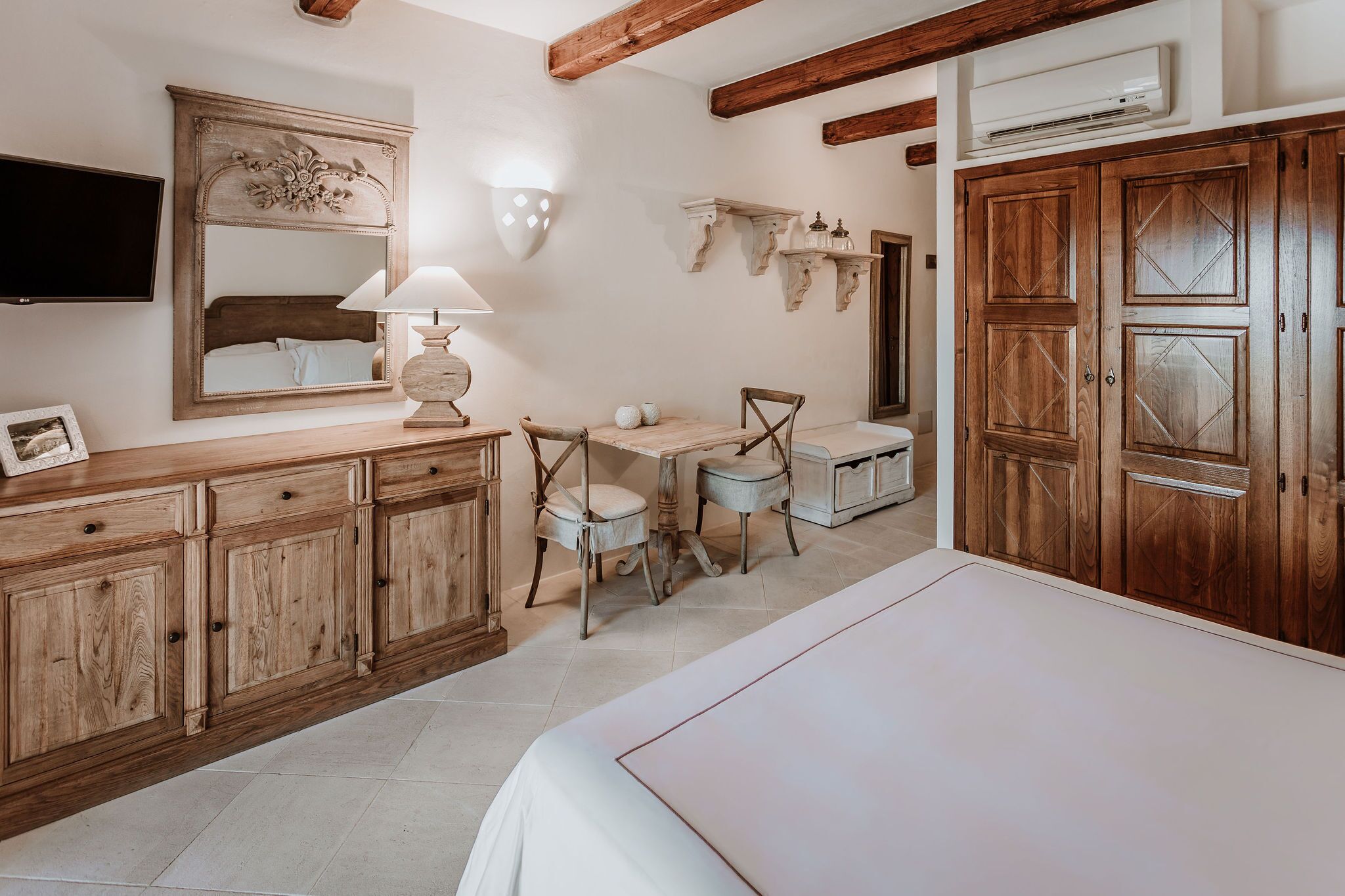 Un dormitorio con cama, armario de madera, mesita de noche, lámpara y televisor.
