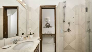 A bathroom with a large mirror, a sink, a shower, and a vanity with a mirror.