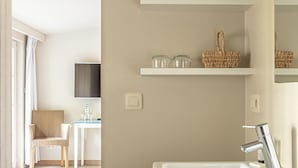 A modern bathroom with a white sink, shelves with towels, and a wicker basket. - Sparhof (Heuvelland)