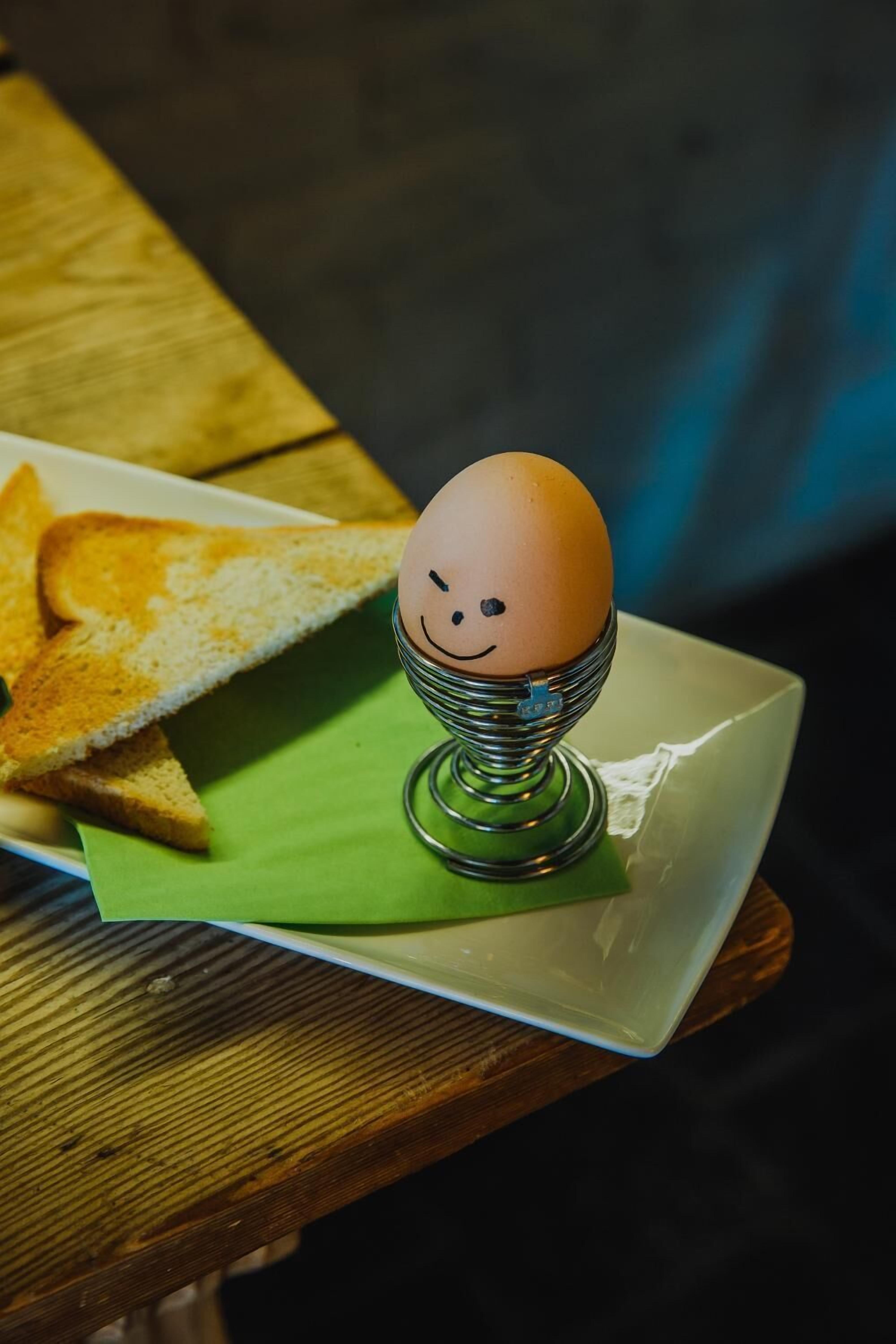 A plate with a toast and a decorative egg holder on a green napkin.