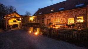 A rustic building with a stone oven, a wooden porch, and a gravel driveway. - Sparhof (Heuvelland)