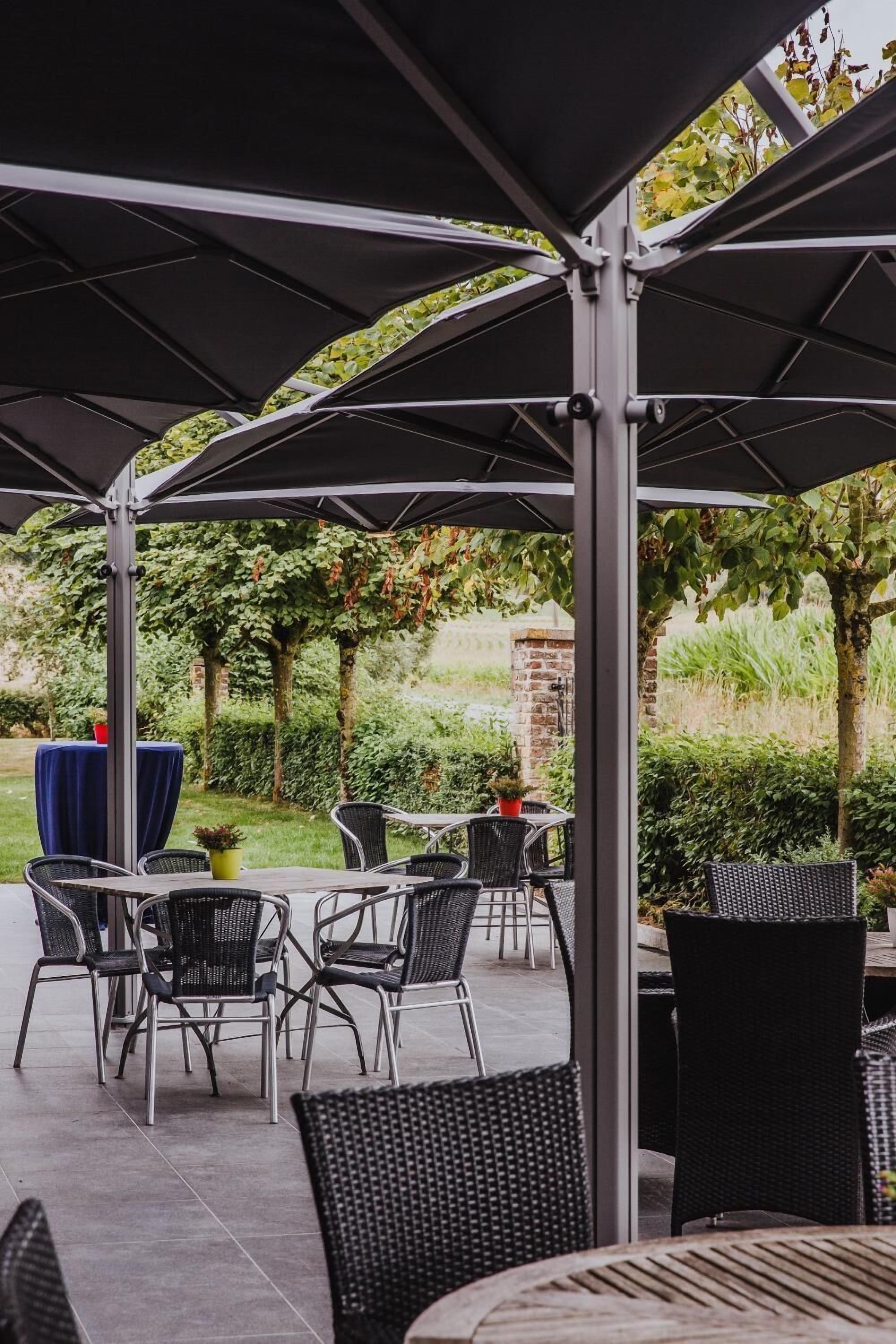 An outdoor patio area with tables and chairs under a covered structure.