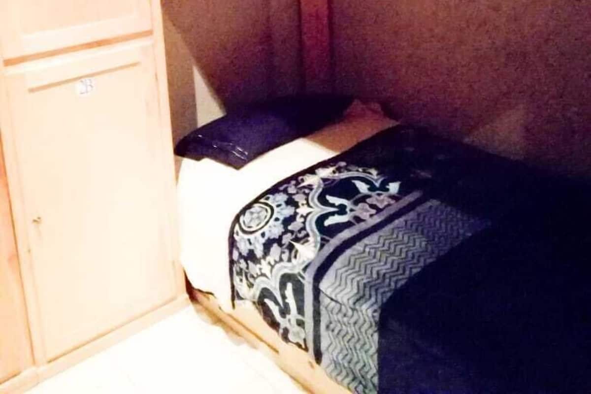 Un lit superposé avec une tête de lit en bois et un lit inférieur doté de draps à motifs.