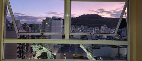 Vista de un paisaje urbano a través de una ventana, con una montaña al fondo.