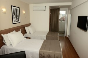 A hotel room with two beds, a framed picture on the wall, an air conditioning unit, and a TV mounted on the wall.