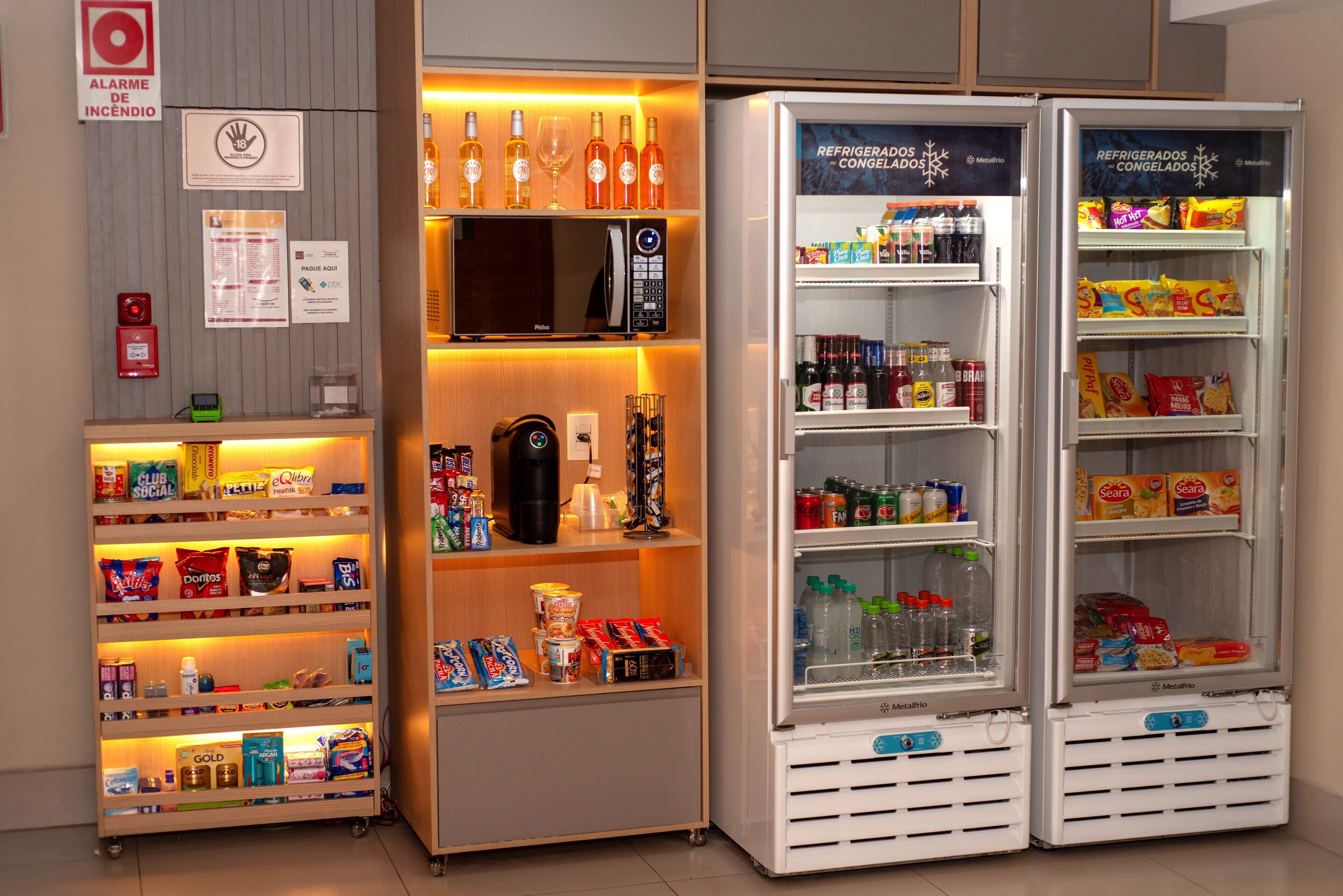 A hotel minibar with a variety of snacks, drinks, and a coffee machine.