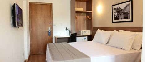 Habitación de hotel con cama, escritorio, armario y televisor.