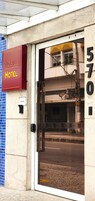 The entrance to a hotel with a glass door, a sign indicating it's a 'Noble Hotel', and the address '570' visible on the wall.