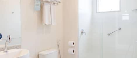 A modern bathroom with a glass-enclosed shower, a white toilet, and a sink with a marble countertop.