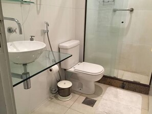 Un bagno con lavabo in vetro, toilette e zona doccia.