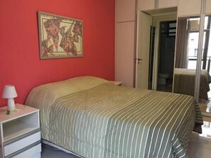 Una camera da letto con un letto, un comodino, una lampada e una porta che dà su un bagno.