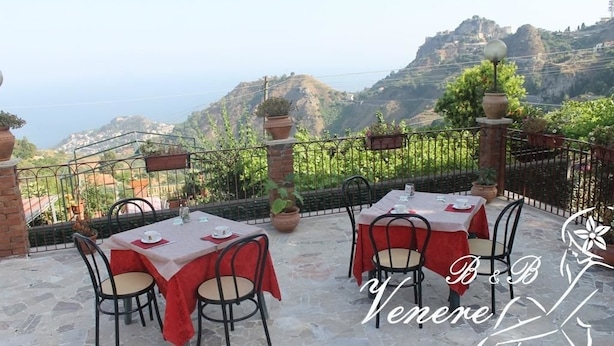 An outdoor terrace with tables and chairs, overlooking a mountainous landscape. - Venere B&B Castelmola (Castelmola)