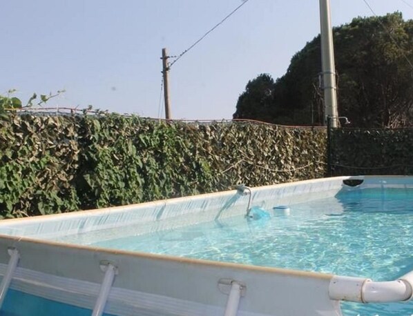 A rectangular swimming pool with clear blue water, surrounded by a hedge. - Venere B&B Castelmola (Castelmola)