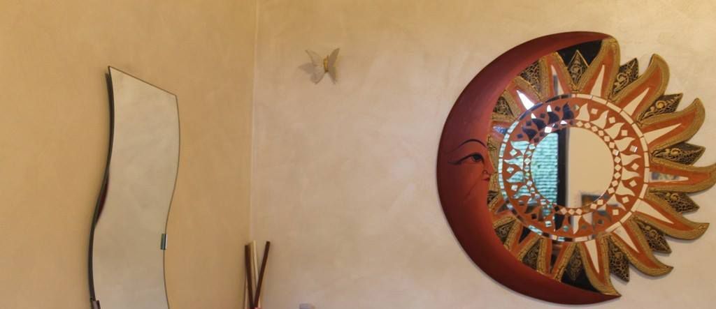 Un mur orné d’un miroir en forme de croissant et d’une sculpture abstraite contemporaine.