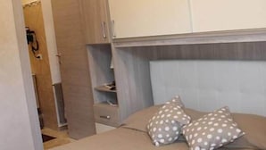 A bedroom with a bed, two pillows, a wardrobe, and a small shelf. - Venere B&B Castelmola (Castelmola)