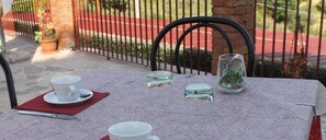 A table set with a white cup, a saucer, and a red napkin. There are three glass jars on the table, one with a plant. - Venere B&B Castelmola (Castelmola)