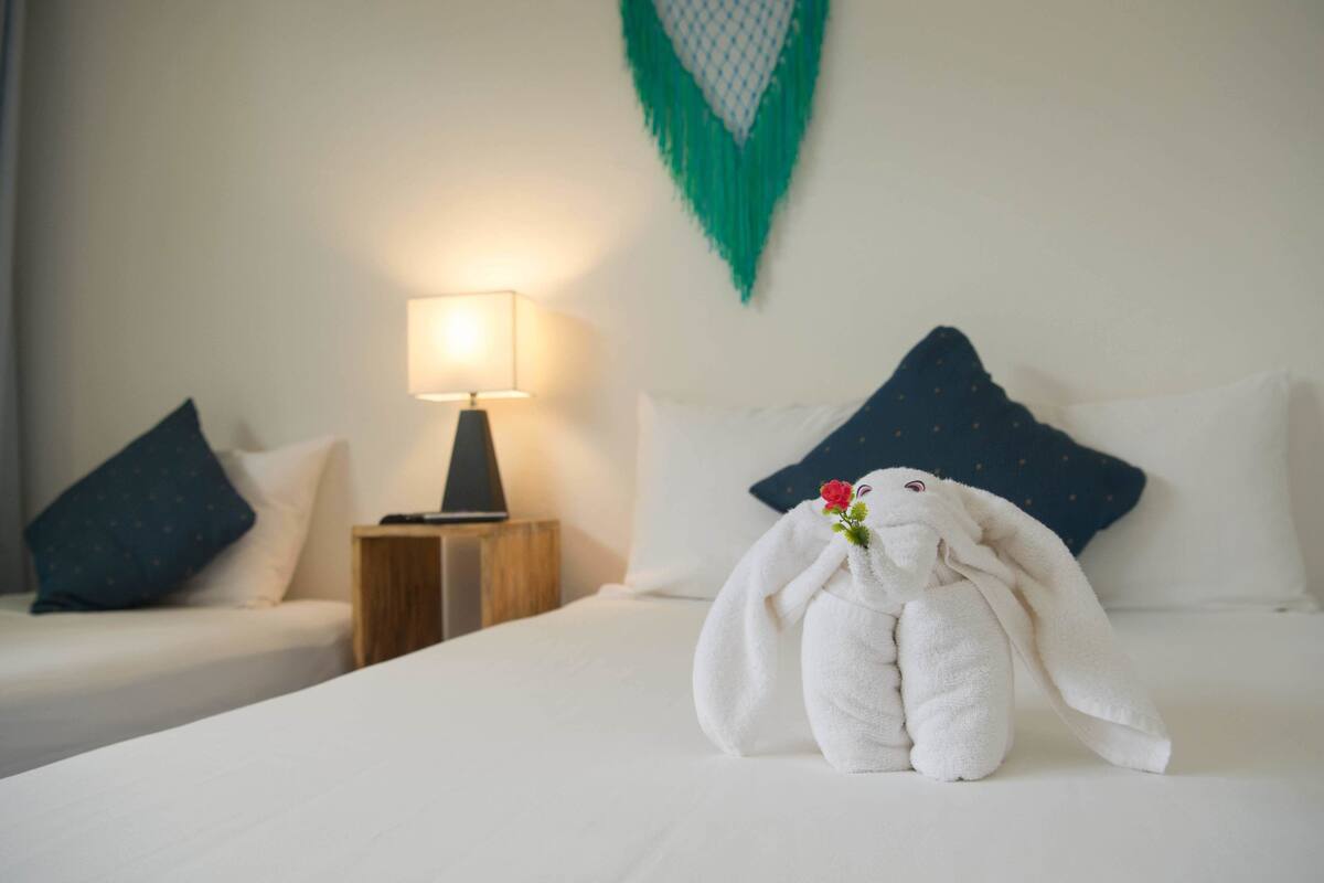 Una habitación de hotel con una cama bien hecha, una lámpara de noche y un adorno en la pared.