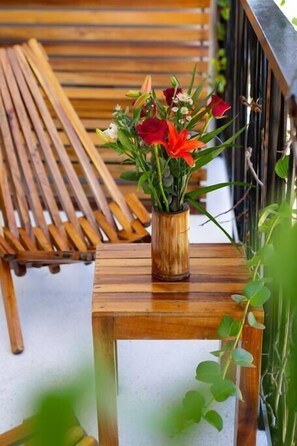 Un banc en bois et une petite table sur laquelle se trouve un vase en bois contenant des fleurs.