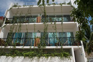 Un immeuble à plusieurs étages dont les balcons sont recouverts de verdure.