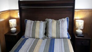 A bed with a striped bedspread, two pillows, and two bedside lamps. - House para 4 en Concon (Concon)