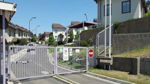 A gated entrance to a residential area with houses in the background and a sign reading "BAHIA OCEANOS 039". - House para 4 en Concon (Concon)