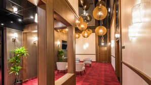 Un pasillo con alfombra roja, paredes de madera y luminarias modernas.