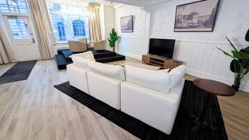 Uma sala de estar moderna com sofá, TV e obras de arte na parede.