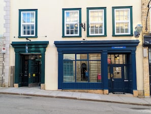 A building with a blue facade, a door with a sign, and a window with a sign. - Hotel Manoir Morgan (Québec City)