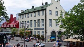 A historic building with a sign for tourist information, a street with pedestrians, and a café with outdoor seating.