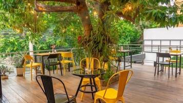 Une terrasse extérieure avec un sol en bois, des chaises et des tables jaunes et noires.