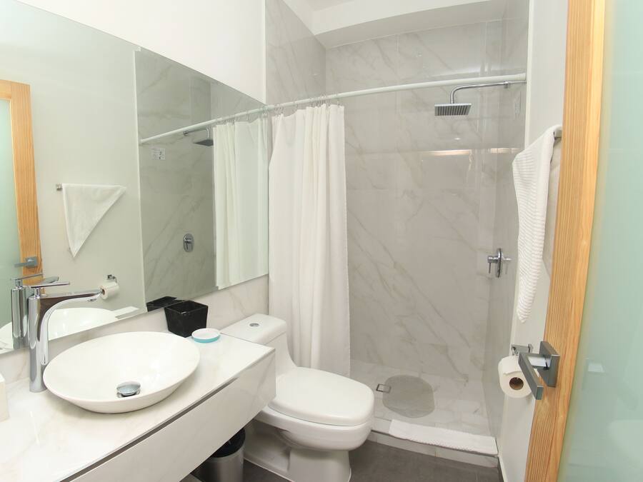 A modern bathroom with a white sink, toilet, and shower.