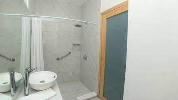 Un baño con lavamanos, espejo y ducha blancos.