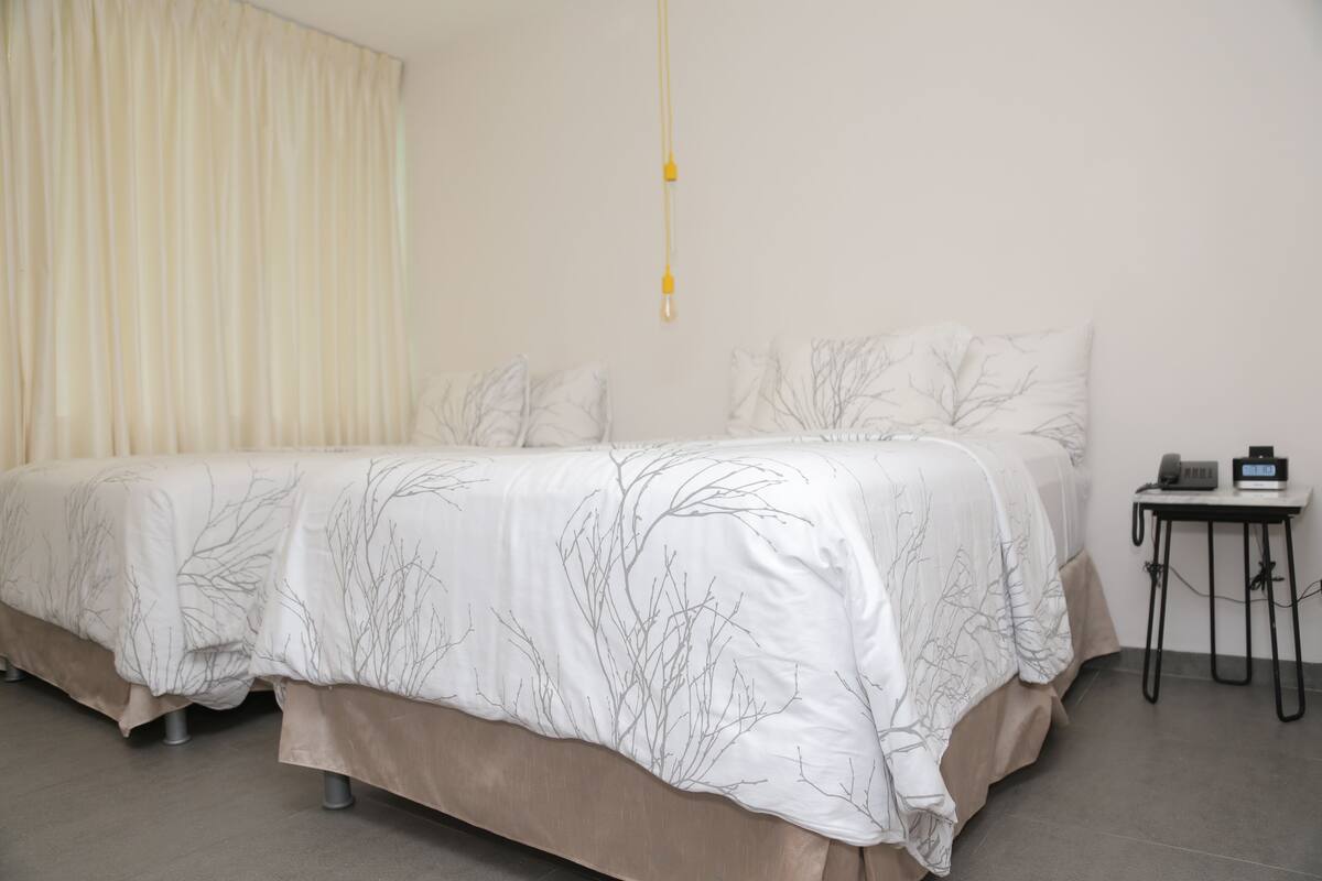 A bedroom with a bed, a bedside table, and a hanging light fixture.