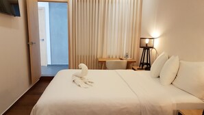 Een hotelkamer met een bed, een bureau, een stoel, een lamp en een televisie aan de muur.
