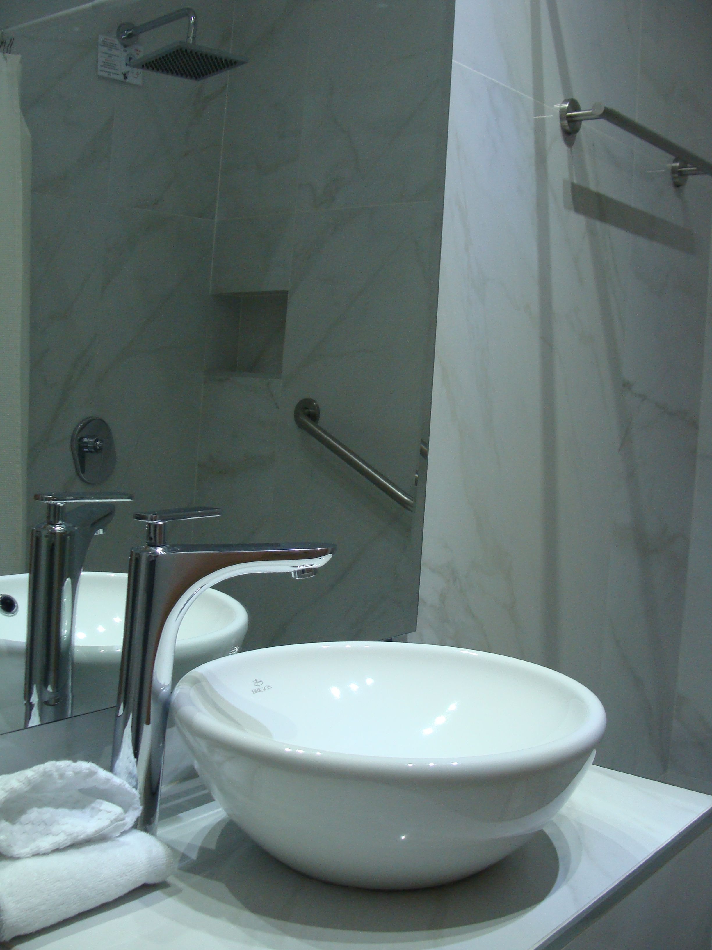 A bathroom with a white sink, a mirror, and a shower.