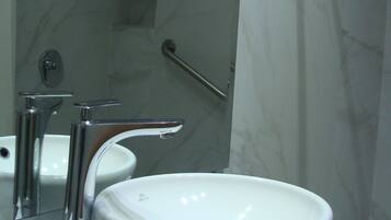 A bathroom with a white sink, a mirror, and a shower.