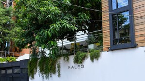 Een gebouw met een witte muur, een zwart hek en de naam 'KALEO'.