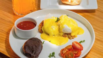 Ein Frühstücksteller mit Eggs Benedict, Toast und Tomaten auf einer Holztischplatte.