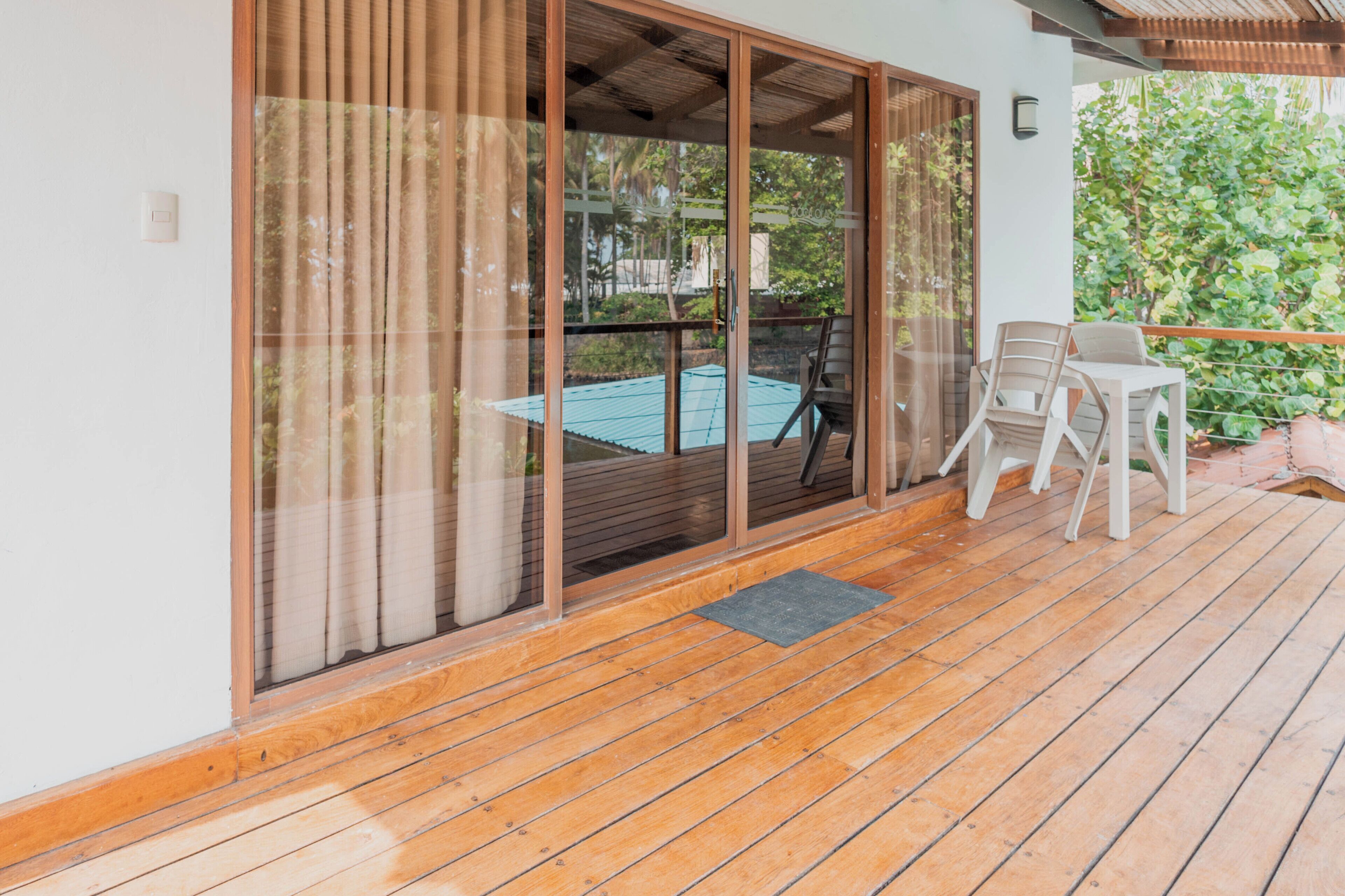 A wooden deck with a sliding glass door leading to a pool area.