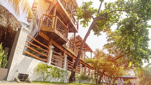 A multi-story building with balconies, surrounded by greenery and a water body. - Boca Olas Resort Villas (Tamanique)