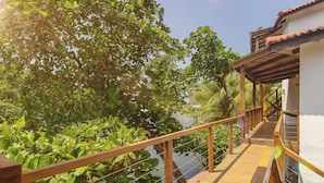 A wooden deck with a railing overlooking a body of water, surrounded by lush greenery. - Boca Olas Resort Villas (Tamanique)