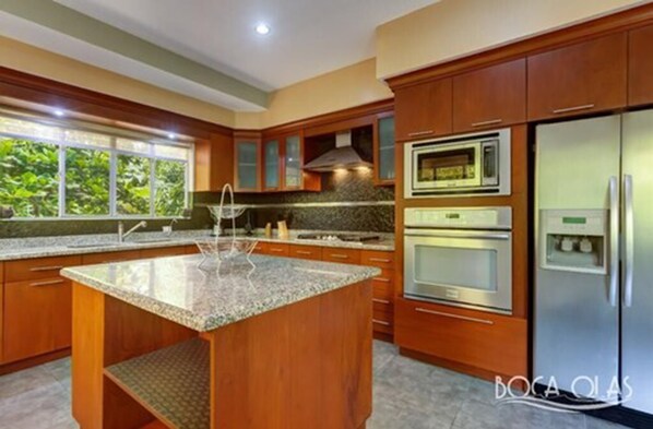 A modern kitchen with granite countertops, stainless steel appliances, and wooden cabinetry.