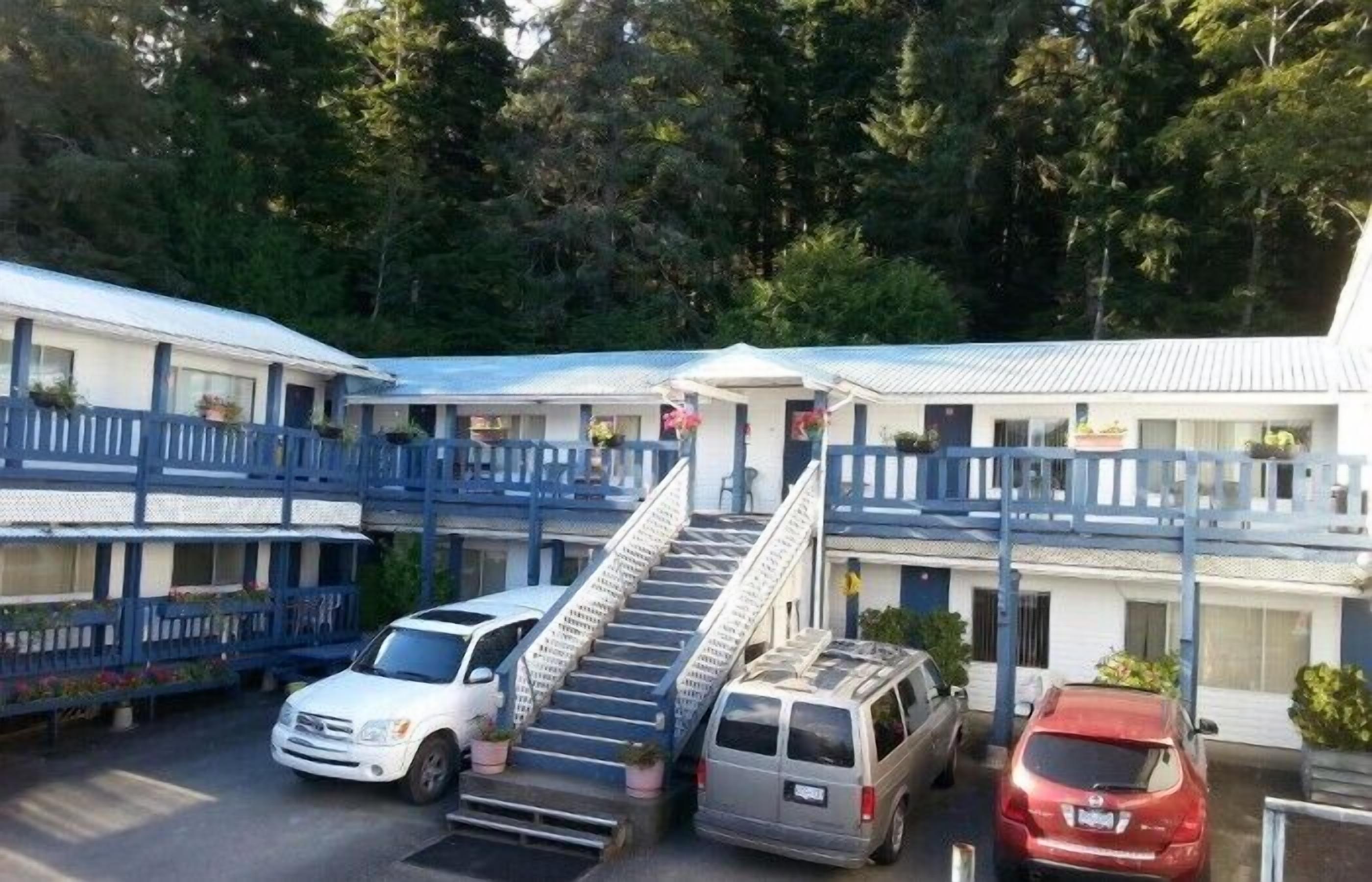 A motel with multiple floors, a central staircase, and a parking area with several vehicles.