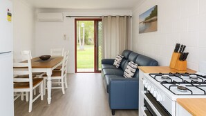 Een kleine keuken met een gasfornuis, een eettafel met stoelen en een blauwe bank.