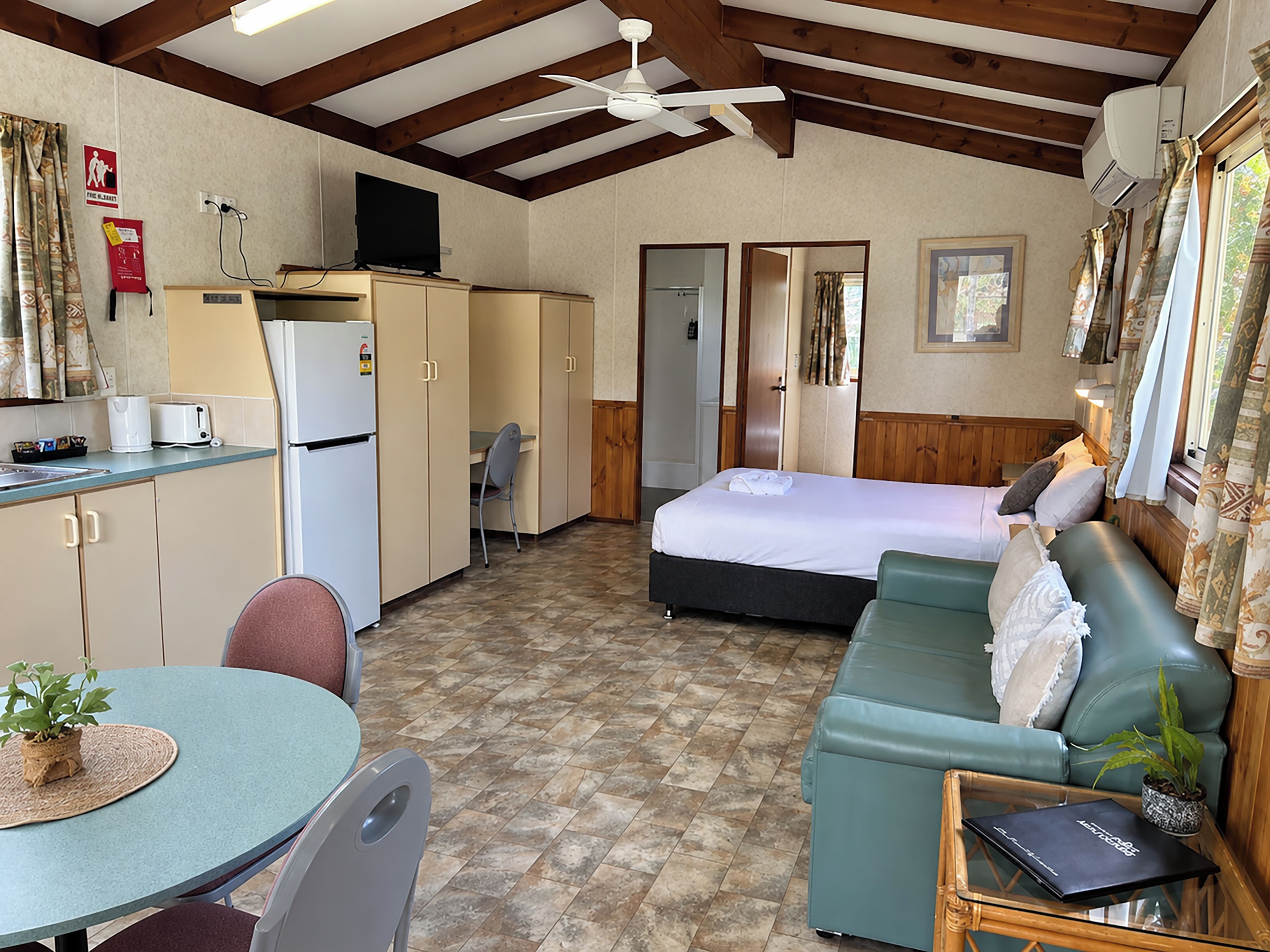 Una habitación compacta con kitchenette, cama, sofá y zona de comedor.