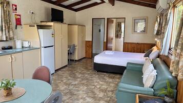Una habitación compacta con kitchenette, cama, sofá y zona de comedor.