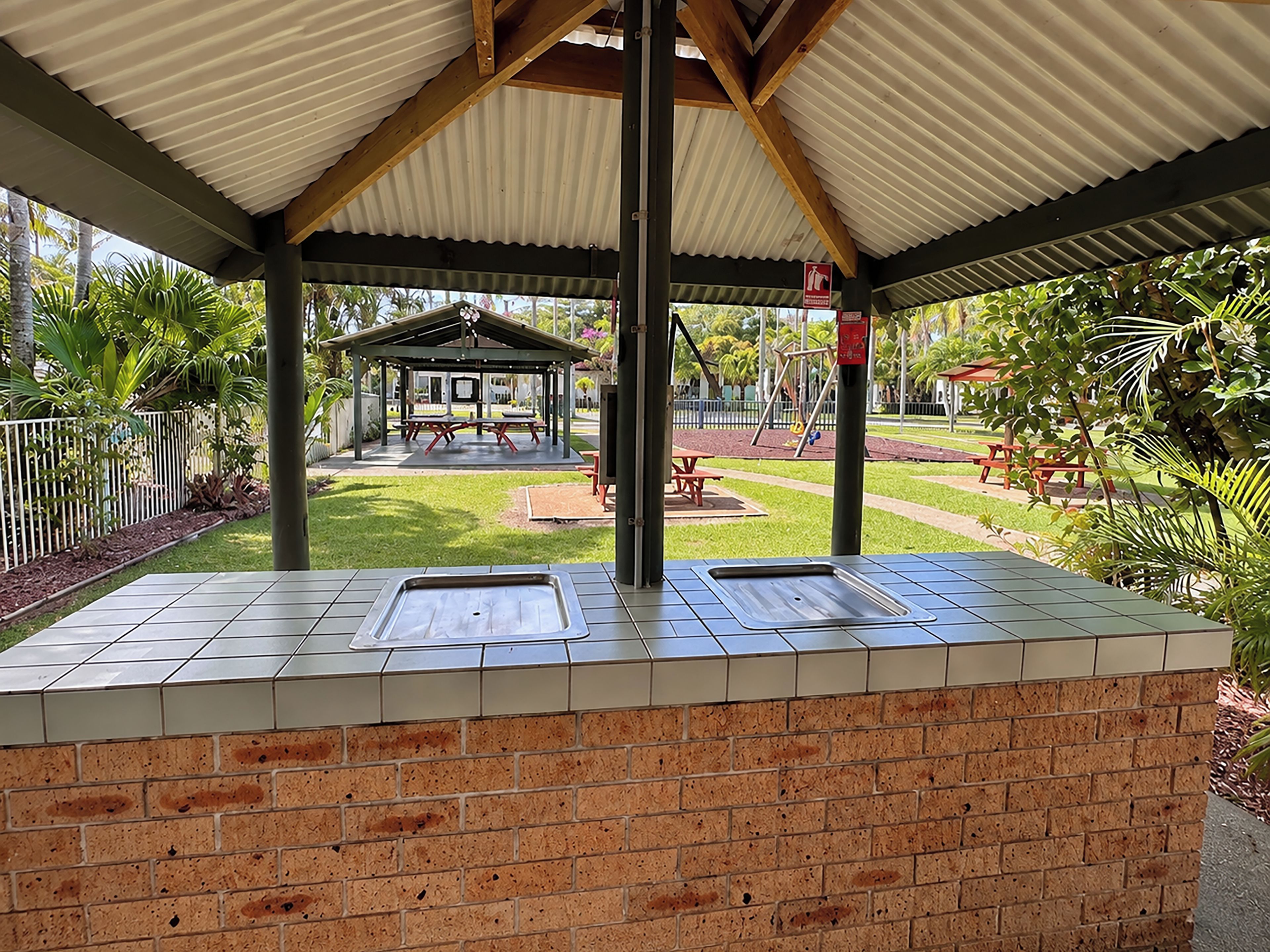 A covered outdoor area with a picnic table and a playground.